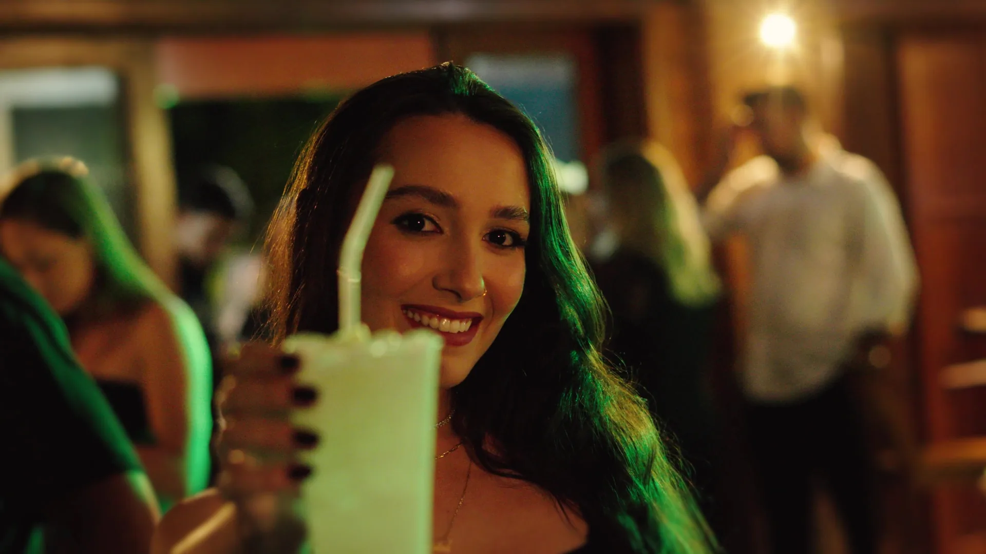 Convidada sorrindo e erguendo um drinque em brinde no evento da Meio Med Vet.